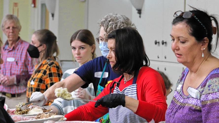  From right, Patricia Taylor, Joanna Tillinghast, and Suzanne Sauer help serve meals as part of volunteer work for Manna Soup Kitchen’s Thanksgiving community meal. More than 100 people volunteered to make the dinner possible, working multiple days to prepare, package and serve the meals.