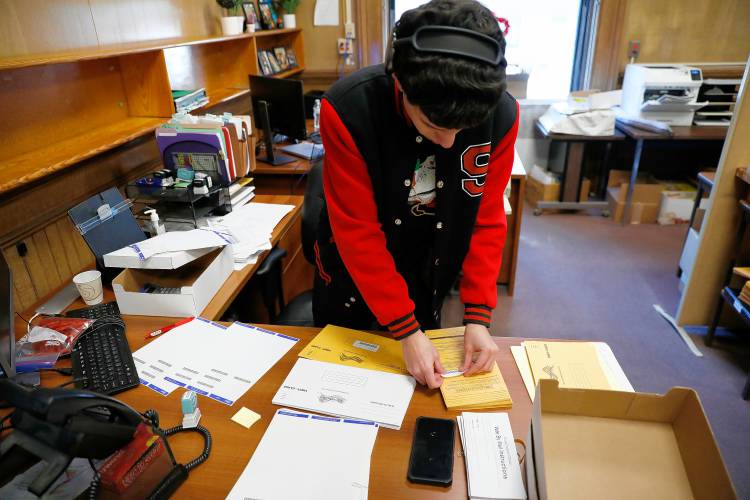 Temp worker Jimmy Serrano preps mail-in ballots Friday at the Holyoke city clerk’s office.