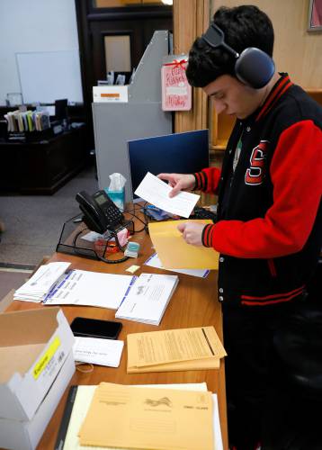 Temporary worker Jimmy Serrano sends out new mail-in ballots Friday afternoon at the Holyoke city clerk’s office.