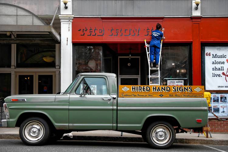 Jess Wissemann of Hired Hand Signs works on hand lettering the facade of the Iron Horse Music Hall on Friday afternoon prior to its reopening. 