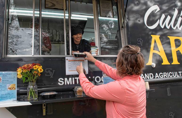 Kara McLaughlin, of Northampton, gets her order from Amarylis Lopez, a junior in the culinary program at Smith Vocational and Agricultural High School. The new food truck opened for business Wednesday and will be open in front  of the school Friday morning and for Friday night’s fall festival. 